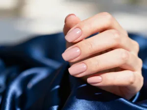 Zadbane dłonie z paznokciami w eleganckim odcieniu przybrudzonego różu, prezentujące modny manicure dla dojrzałych kobiet.